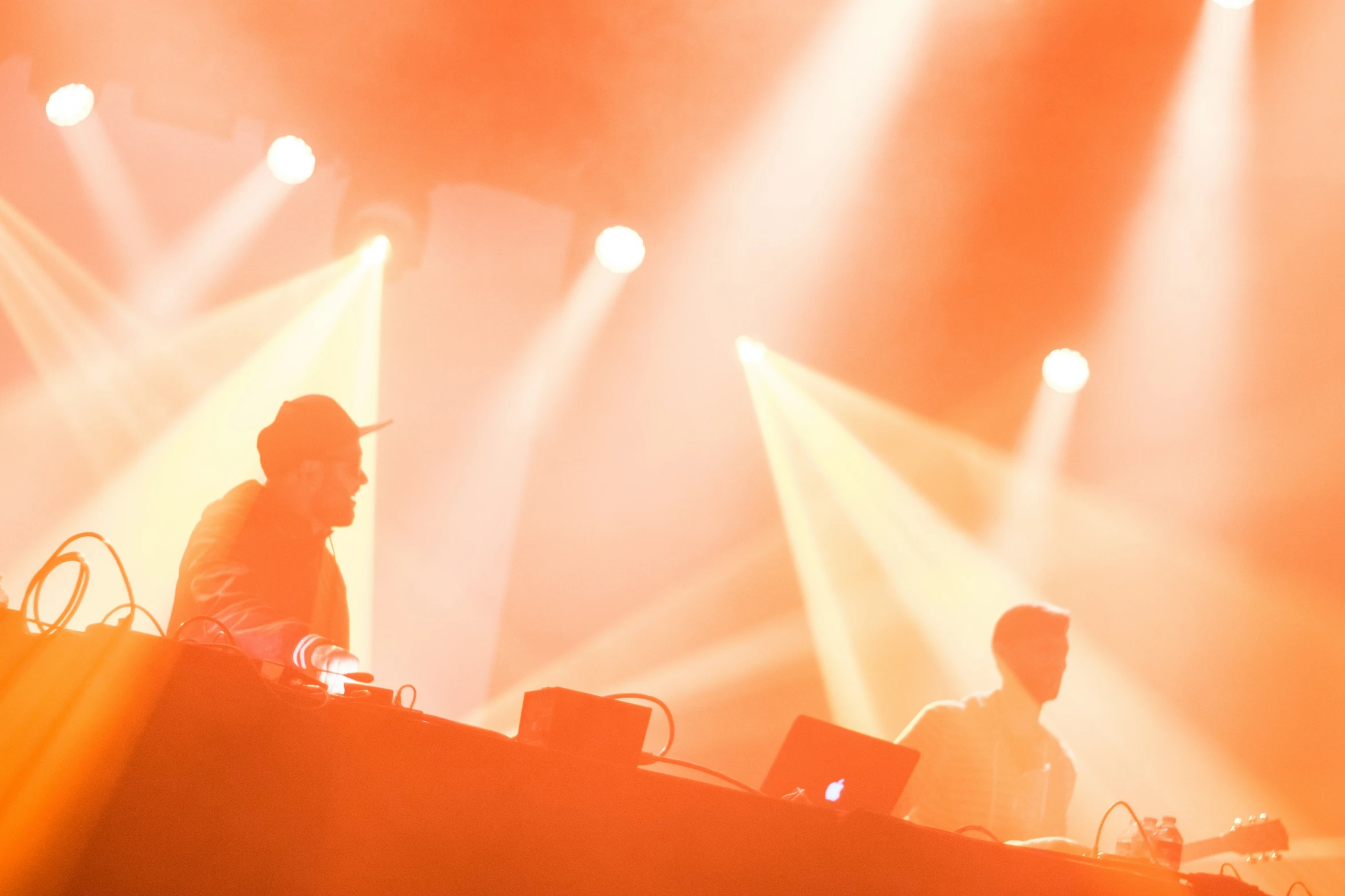 two people are djing on a stage and they have several lights