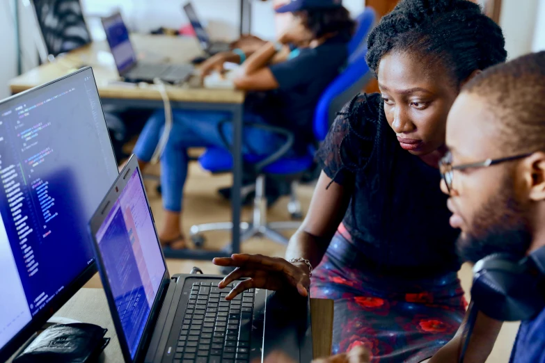 three people work on their laptop computers in an office