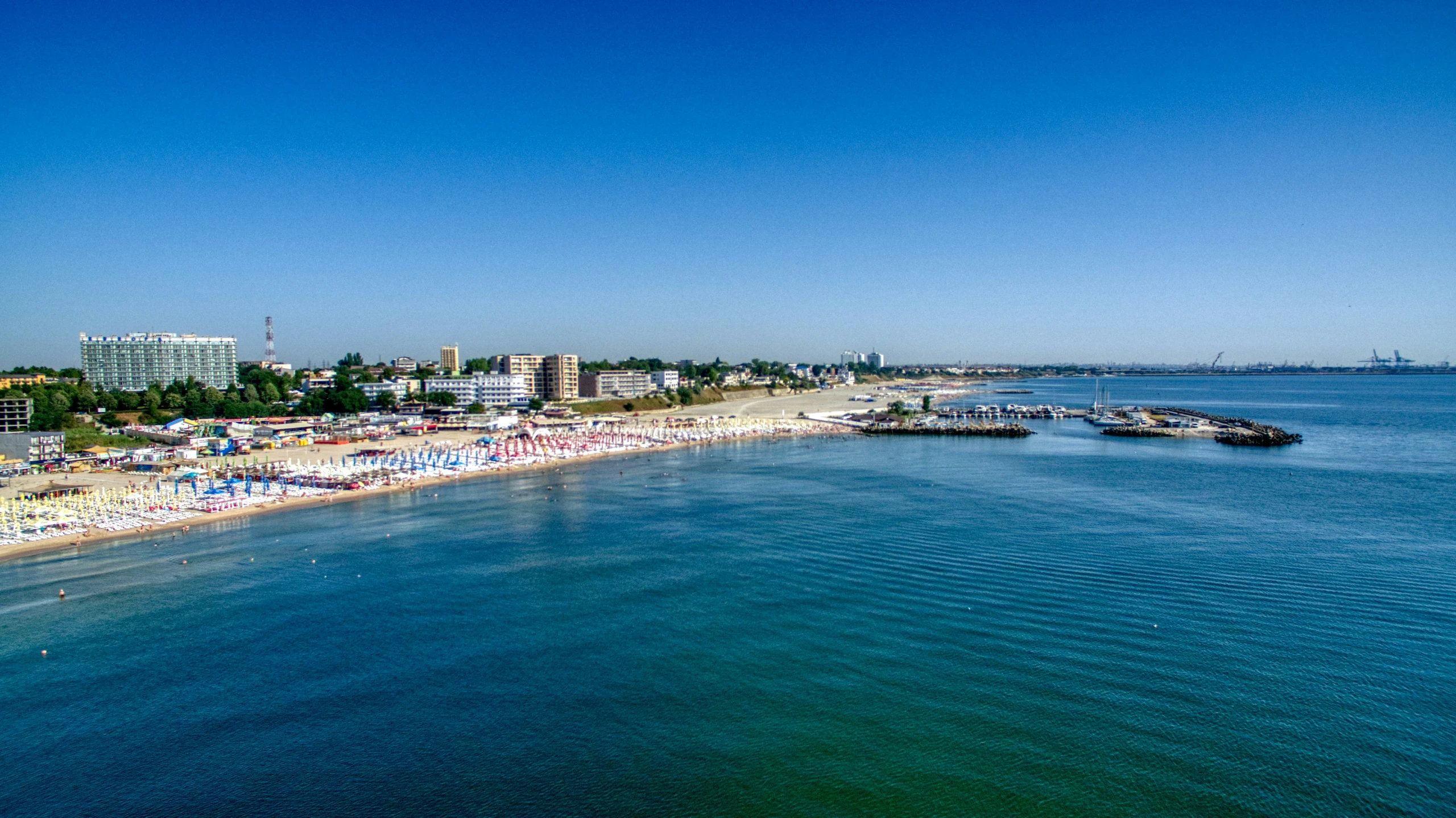 a sandy beach with people on it and a few buildings