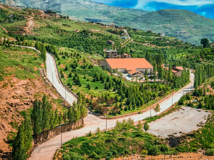 a road winding through some hills with a house in the distance