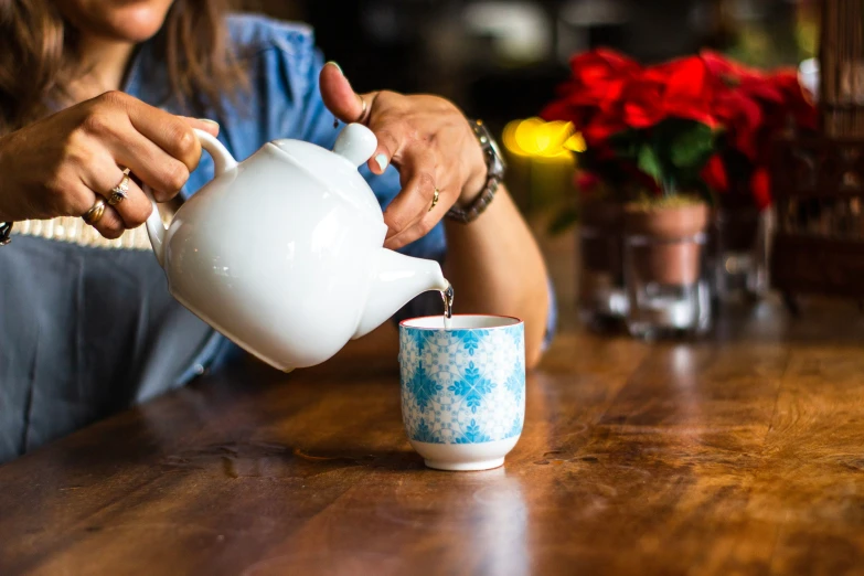 a woman pouring water into a tea cup