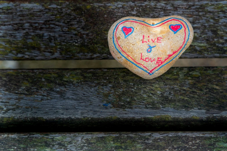 a painted rock sits on a wooden bench