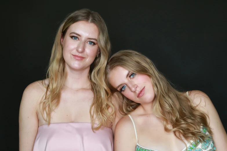 two women are posing for a picture in dresses