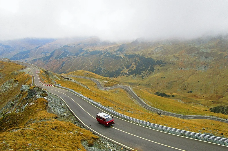 a road that runs into a hill with a bus traveling on it