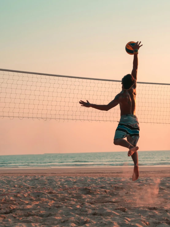 a man reaching up in the air to hit a volleyball
