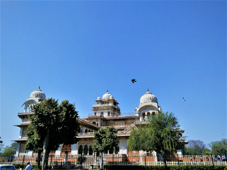 a large white building with domes and several trees