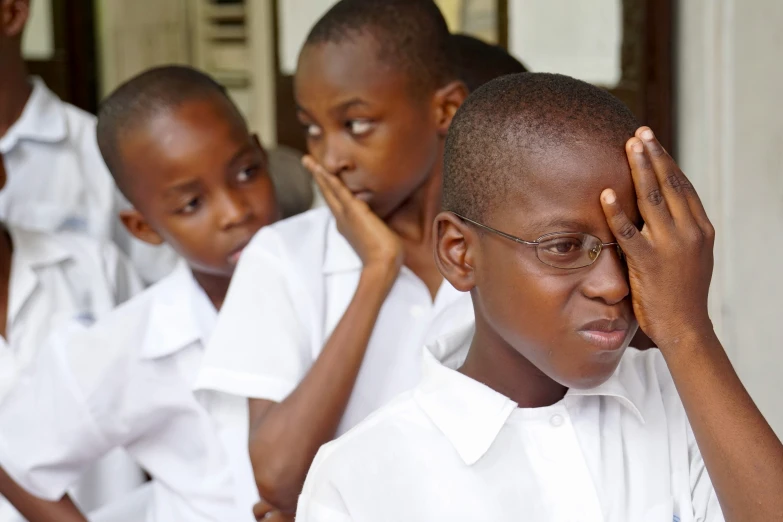 a  holding his head with two other children behind him