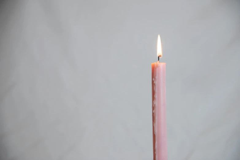 a lit candle on a table with a gray background