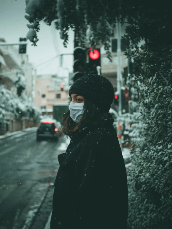 a woman in black standing on the sidewalk