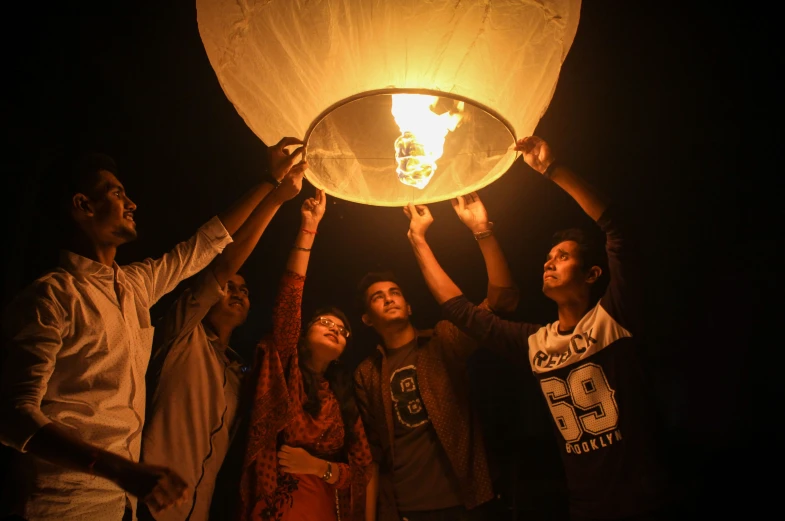 several people hold a lamp up in the night