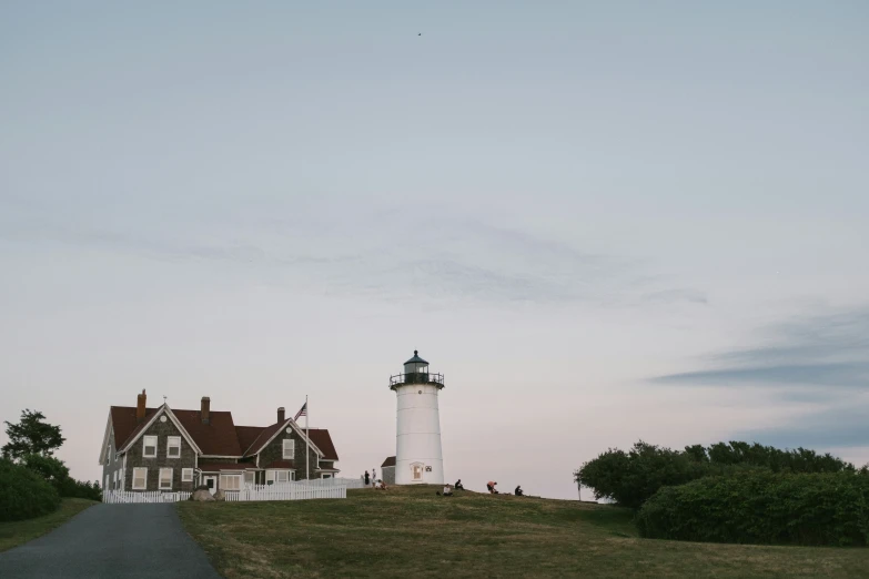 a white lighthouse standing on a hill next to trees