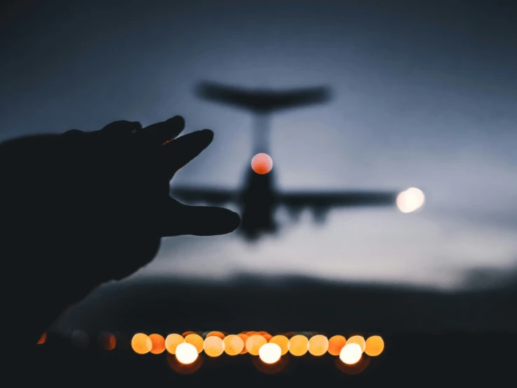 a person is holding a camera with an airplane in the background