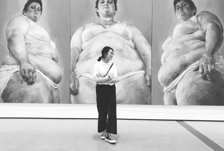 a woman standing in front of three large pictures