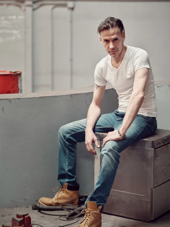 a young man is sitting and wearing boots