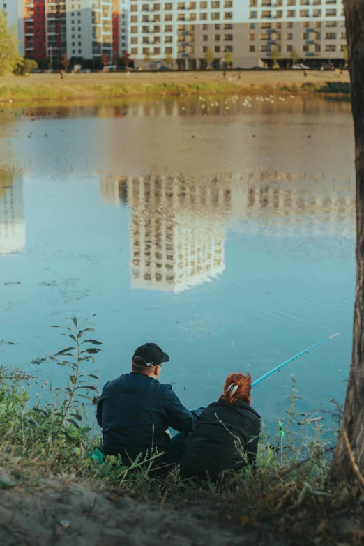 a couple fishing on a lake with the city in the background