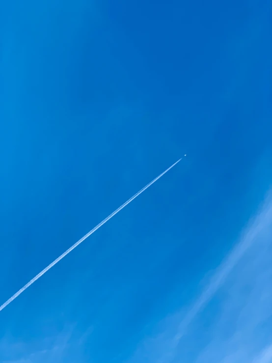 an airplane flying in the blue sky and leaving a trail of smoke