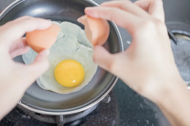 a person is holding an egg and cooking soing in a pan