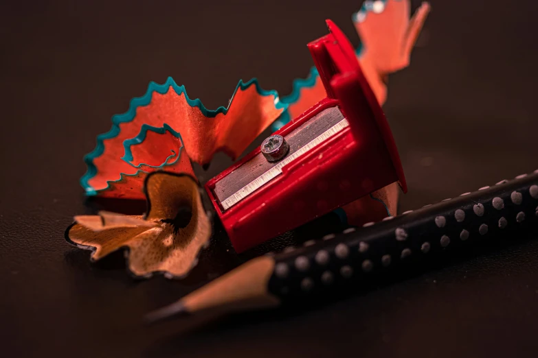 a pencil laying next to some colorful objects on a table