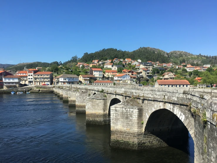 an old bridge over a river in front of a town