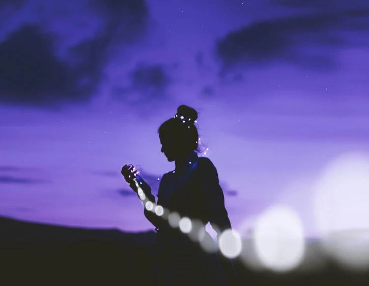 a woman playing guitar in the twilight while the sky is blue