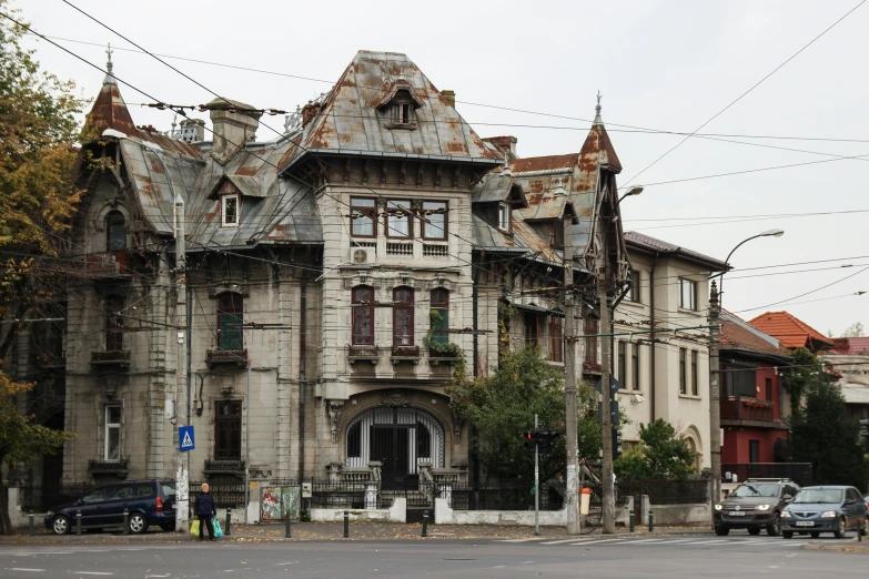 large victorian house on corner with cars parked near it