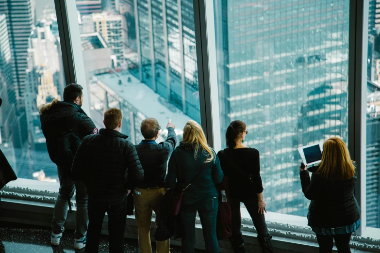 a group of people look out a window over a city