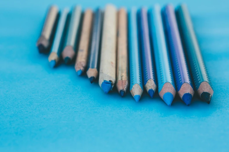 a group of pencils laying in a straight line on a blue surface