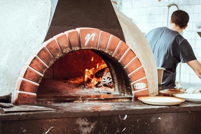 a man cooking over an outdoor pizza oven