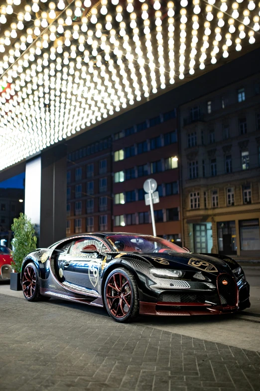 a bugatti parked under a canopy in front of a building at night