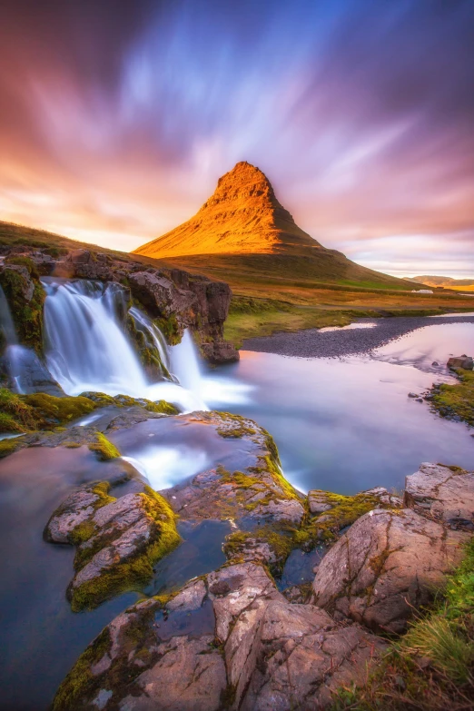 a waterfall in a mountain setting with a blue pond