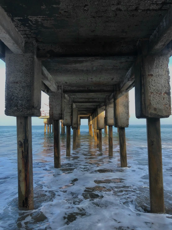 some water waves under a concrete bridge near the beach