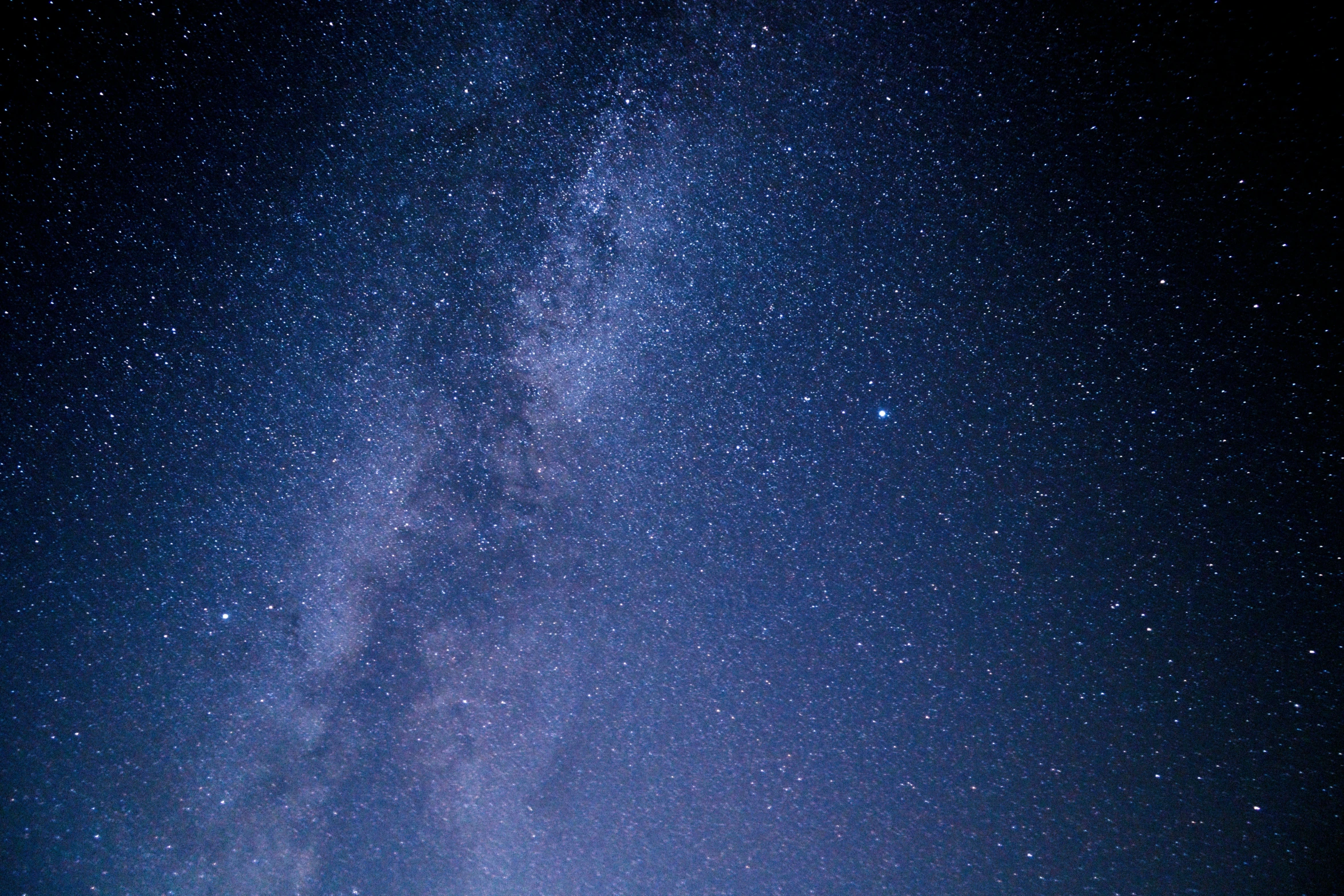 the night sky with a line of stars in the foreground