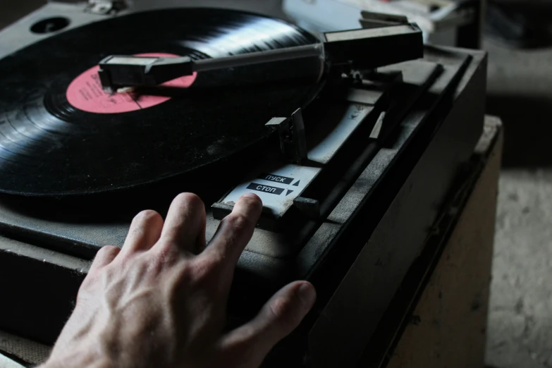 an old turntable with a hand pressing the record
