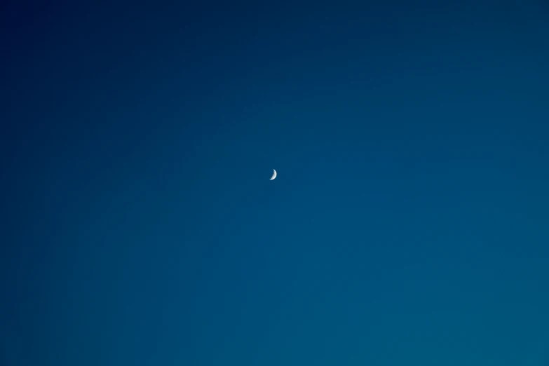 an airplane flying with a moon visible in the sky