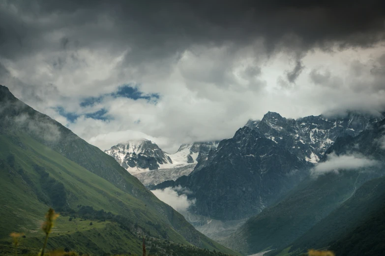 green hills with snow capped mountains on the tops