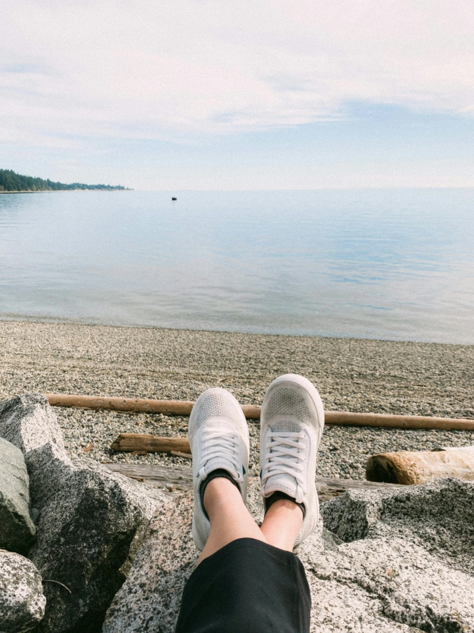 a person's feet and ankles on rocks near the water