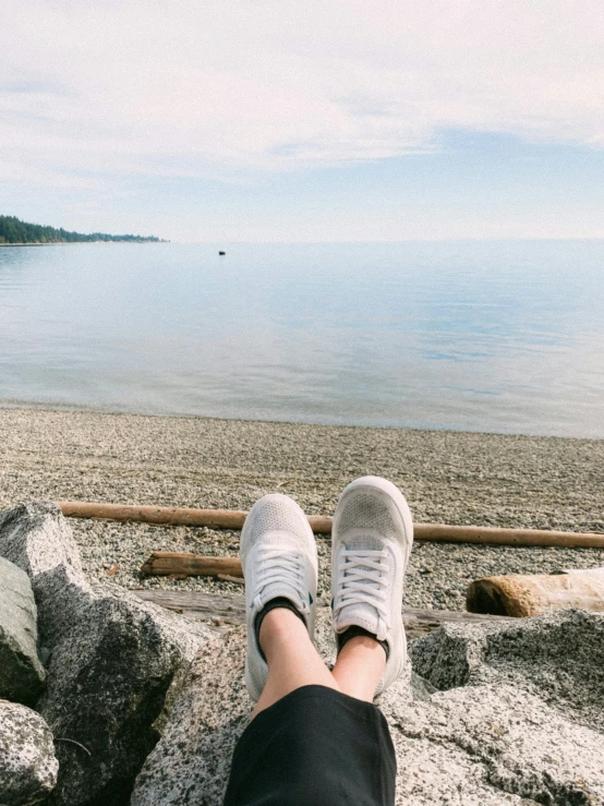 a person's feet and ankles on rocks near the water