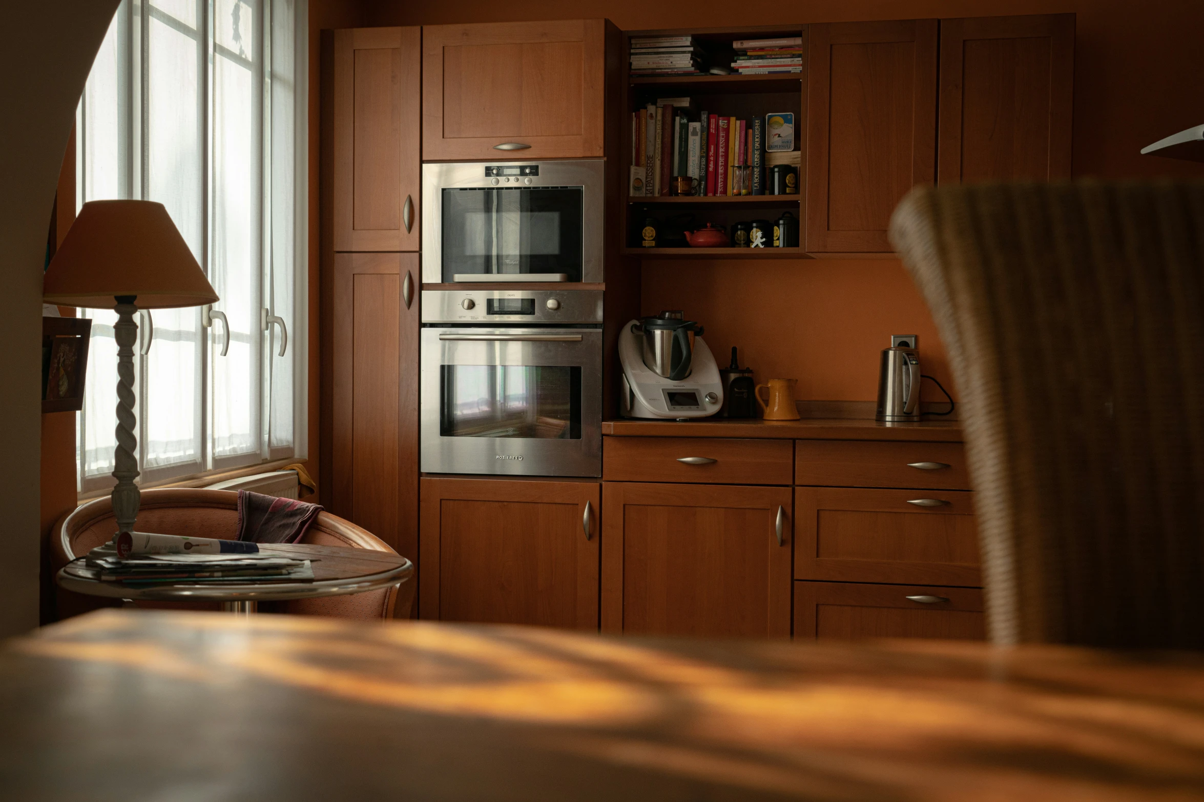 a kitchen with an open bookcase, window, and microwave