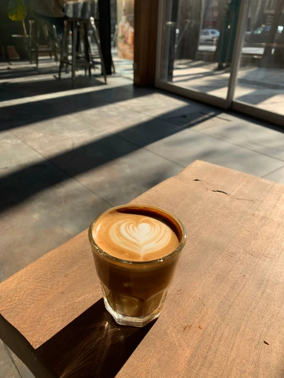 the coffee drink has an intricate design on the foam in a glass