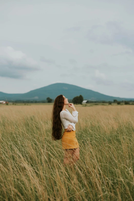 a woman in a yellow skirt is standing in a grassy field