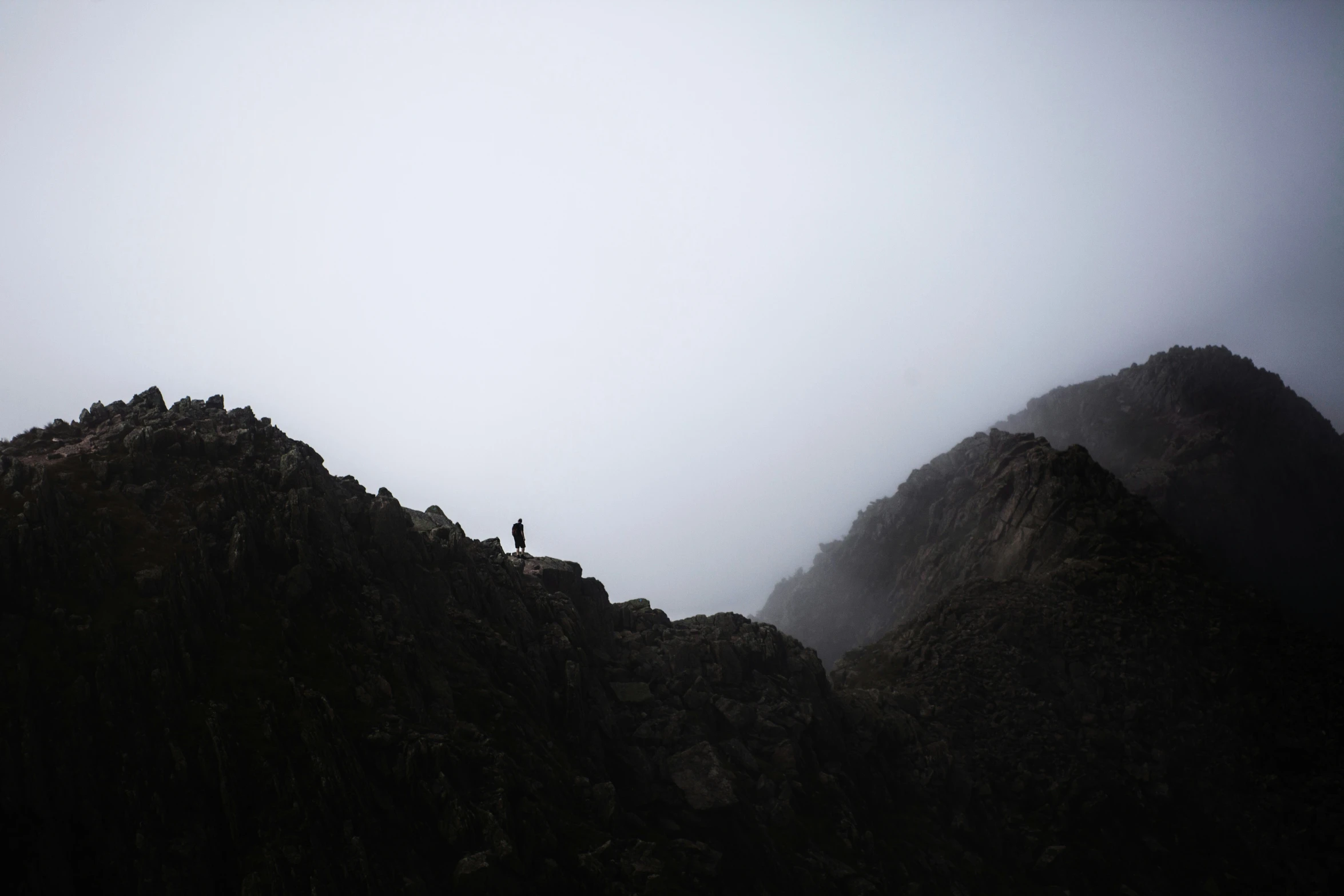 a lone person on top of a mountain surrounded by fog