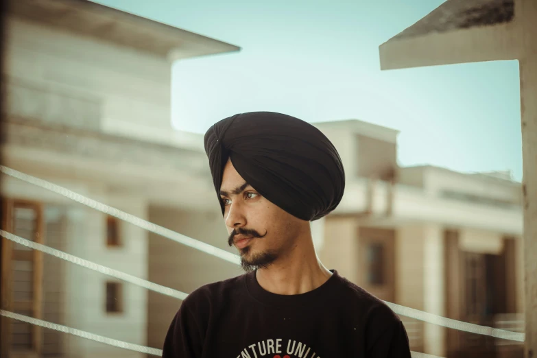 a young man wearing a turban looking off into the distance