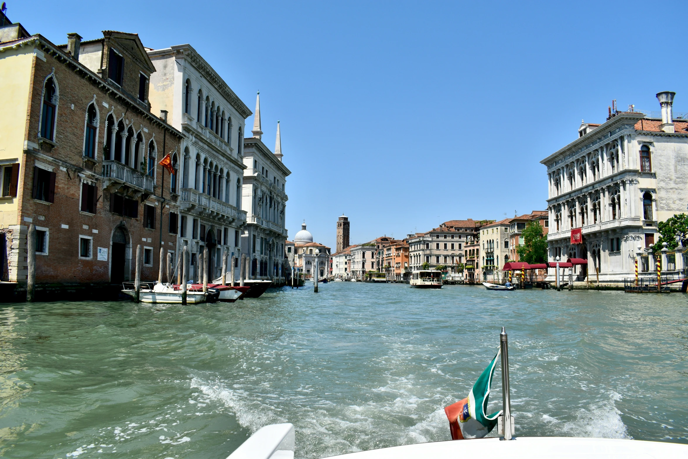 a small boat traveling down the river with a lot of buildings in the back