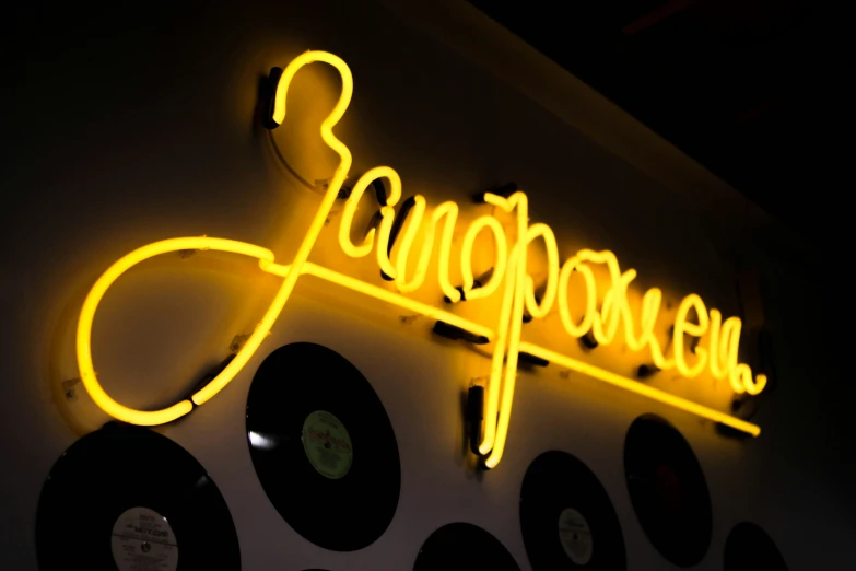 a neon sign is above record players with vinyl records hanging on the wall