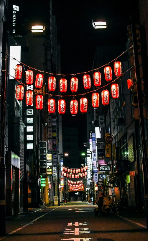a city street with asian lights and red lanterns hanging overhead