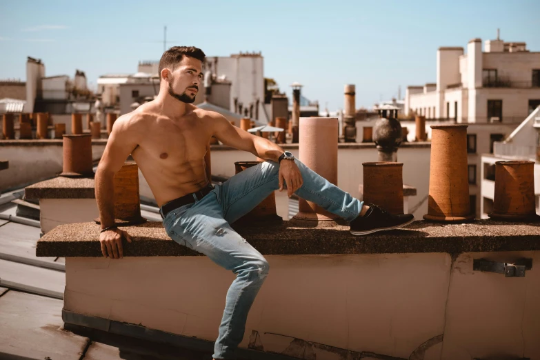 a man in jeans sitting on top of a roof