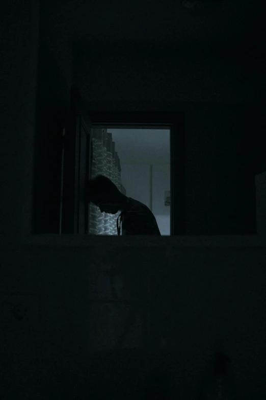 the person in the dark is leaning on a window sill