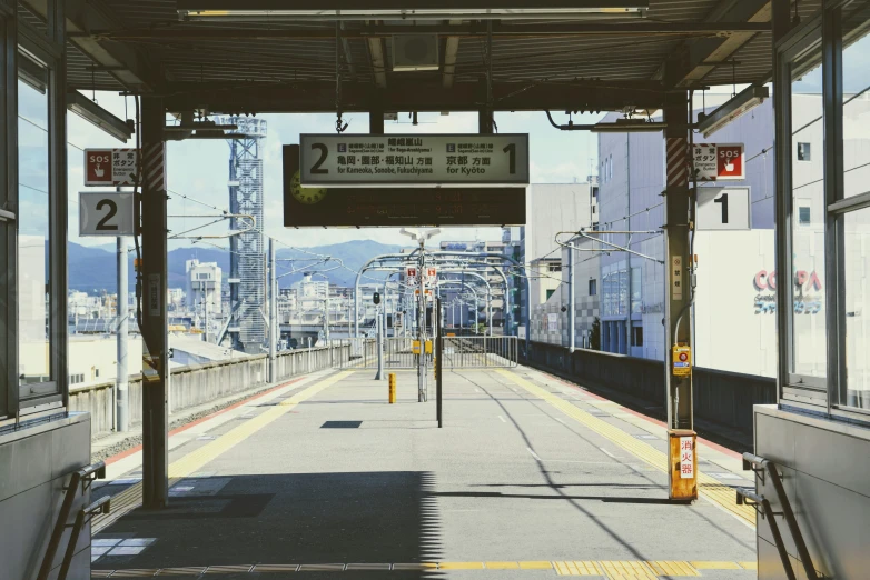 a train station with signs and rails with buildings in the background