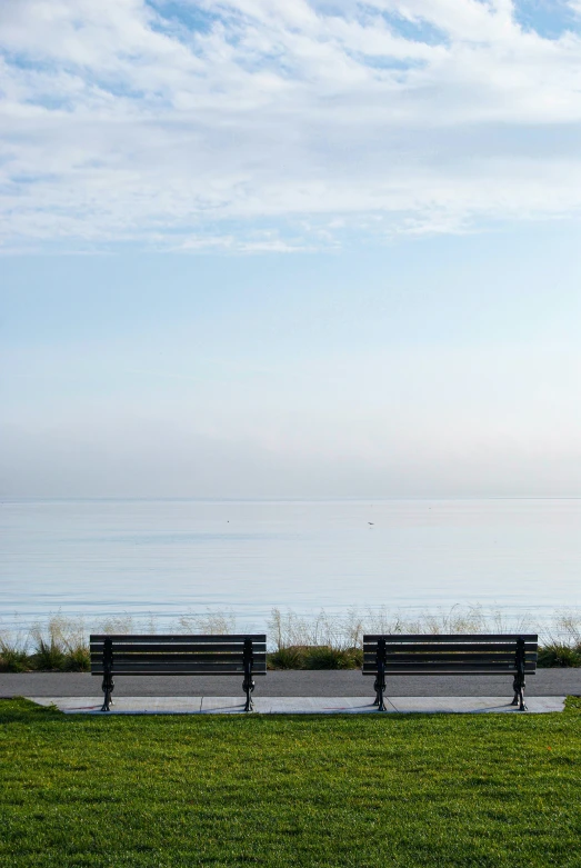 benches and two tables near the water on a beach