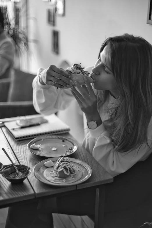 black and white pograph of a woman eating a sandwich